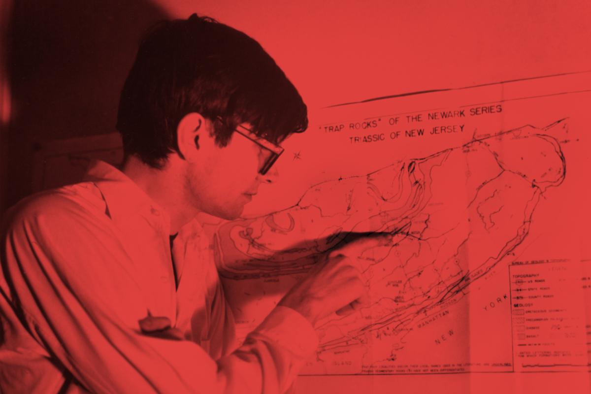 a figure standing next to and pointing at a geologic map of new jersey with a red overlay 