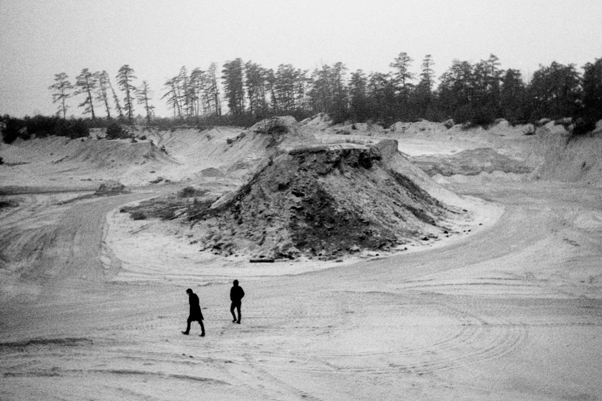 two figures walking through a sand quarry