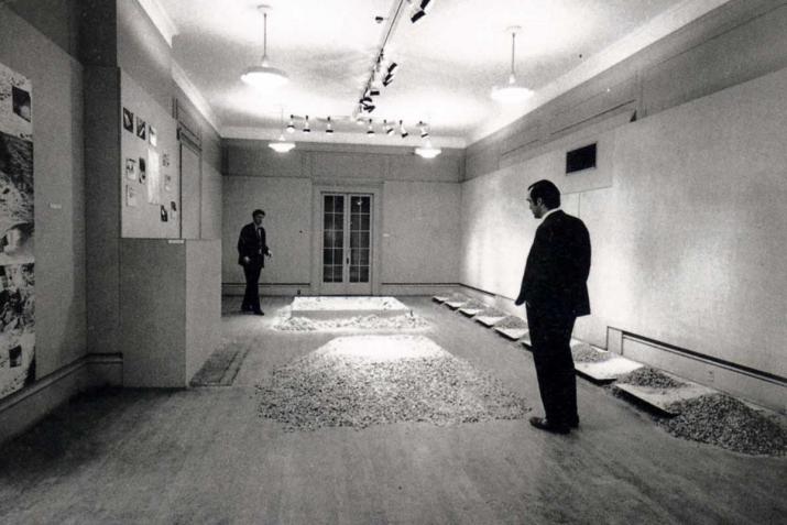 small room with two figures looking at sculptures made of salt and mirrors on the floor, black and white.