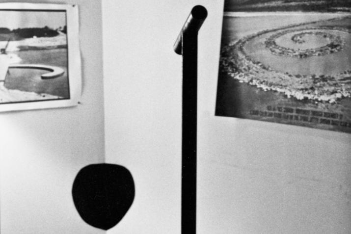 a vertical steel pole with a horizontal viewing pipe directed at a black circle painted in the corner of a room