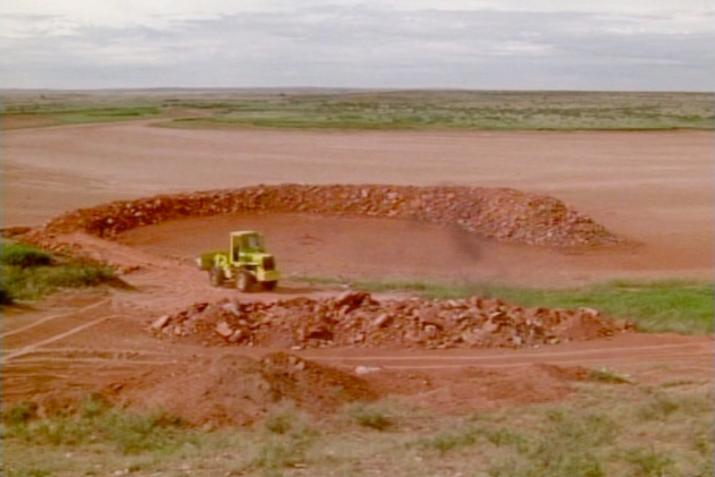 a bulldozer driving on a circular ramp of red earth