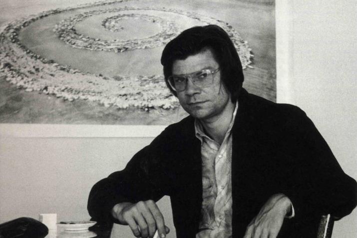 Robert Smithson seated at a table looking at the camera
