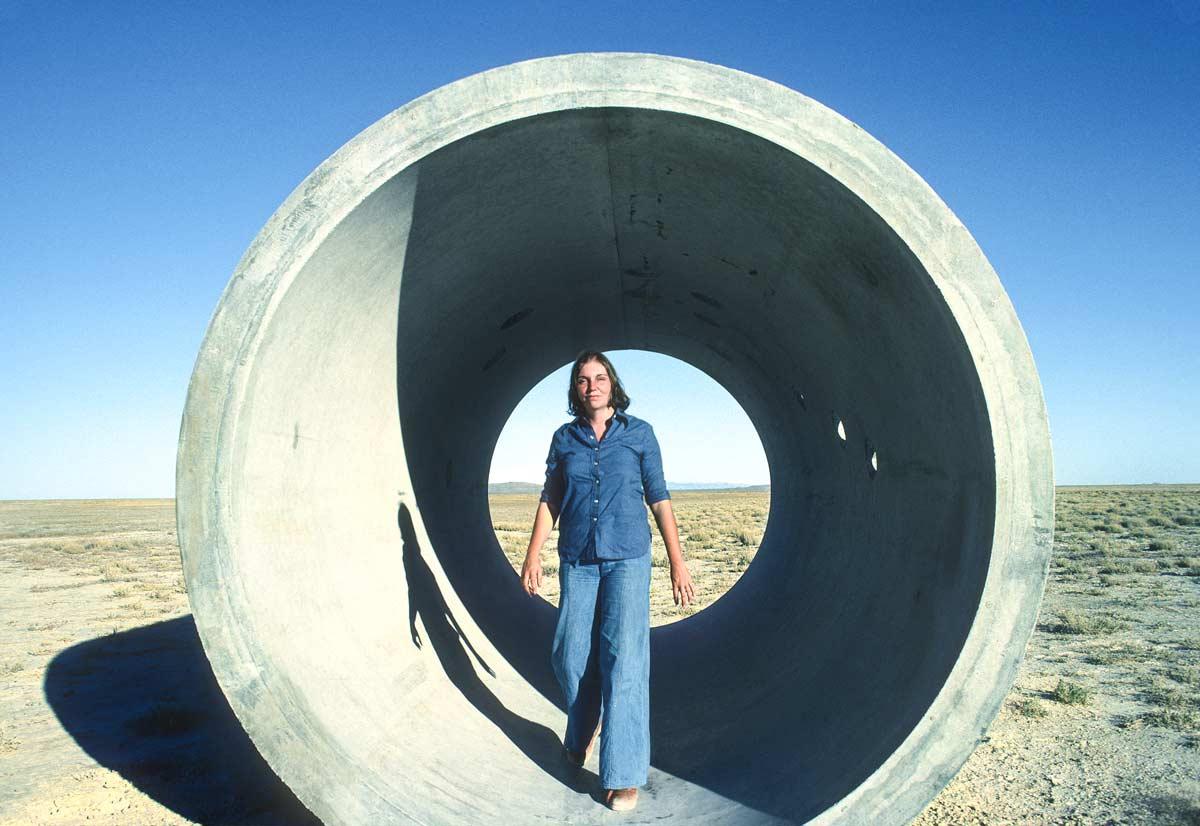 Nancy Holt, dressed in denim and standing in one of the concrete Sun Tunnels, Utah. Photo by Ardele Lister.