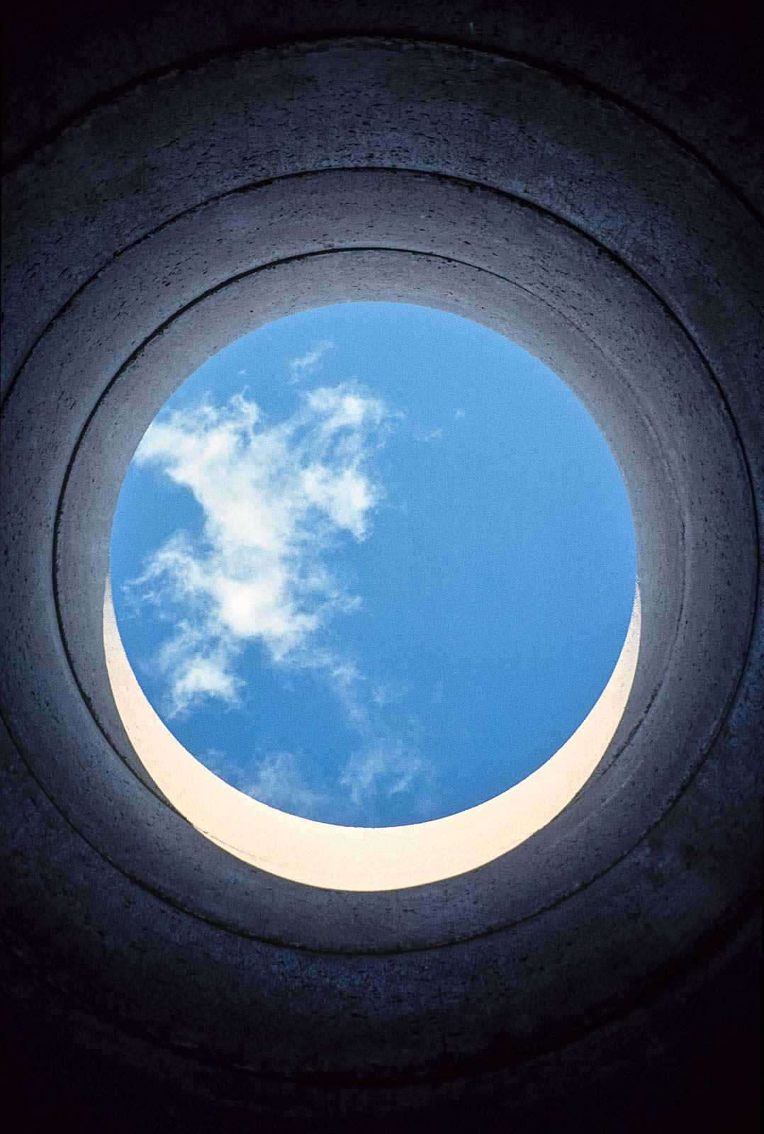 The sky framed by a circular concrete tunnel