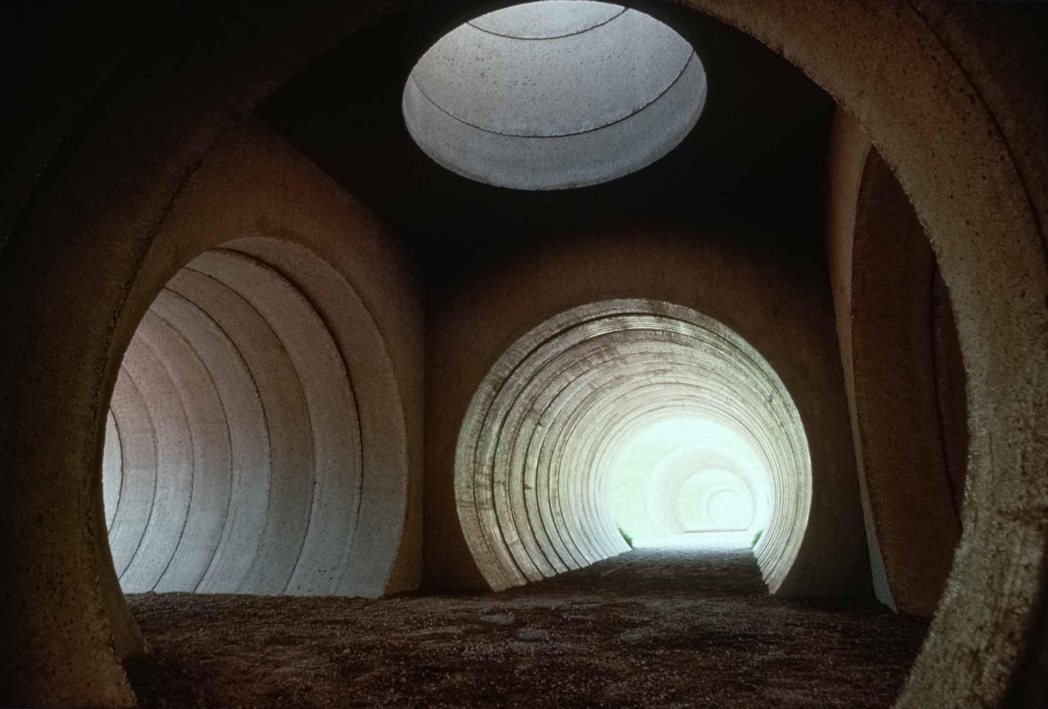 Interior view of converging circular concrete tunnels with light coming through them