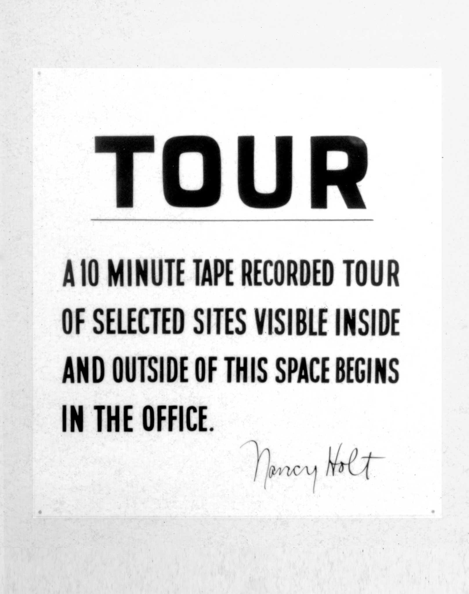 A sign that reads "Tour. a 10 minute tape recorded tour of selected sites visible inside and outside of this space begins in the office"