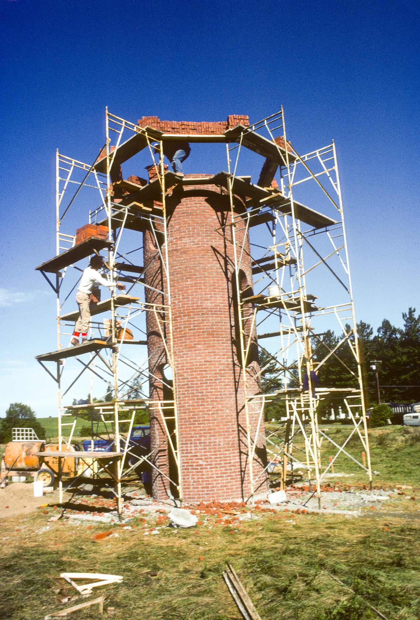 construction image of scaffolding surrounding a tall circular brick structure 