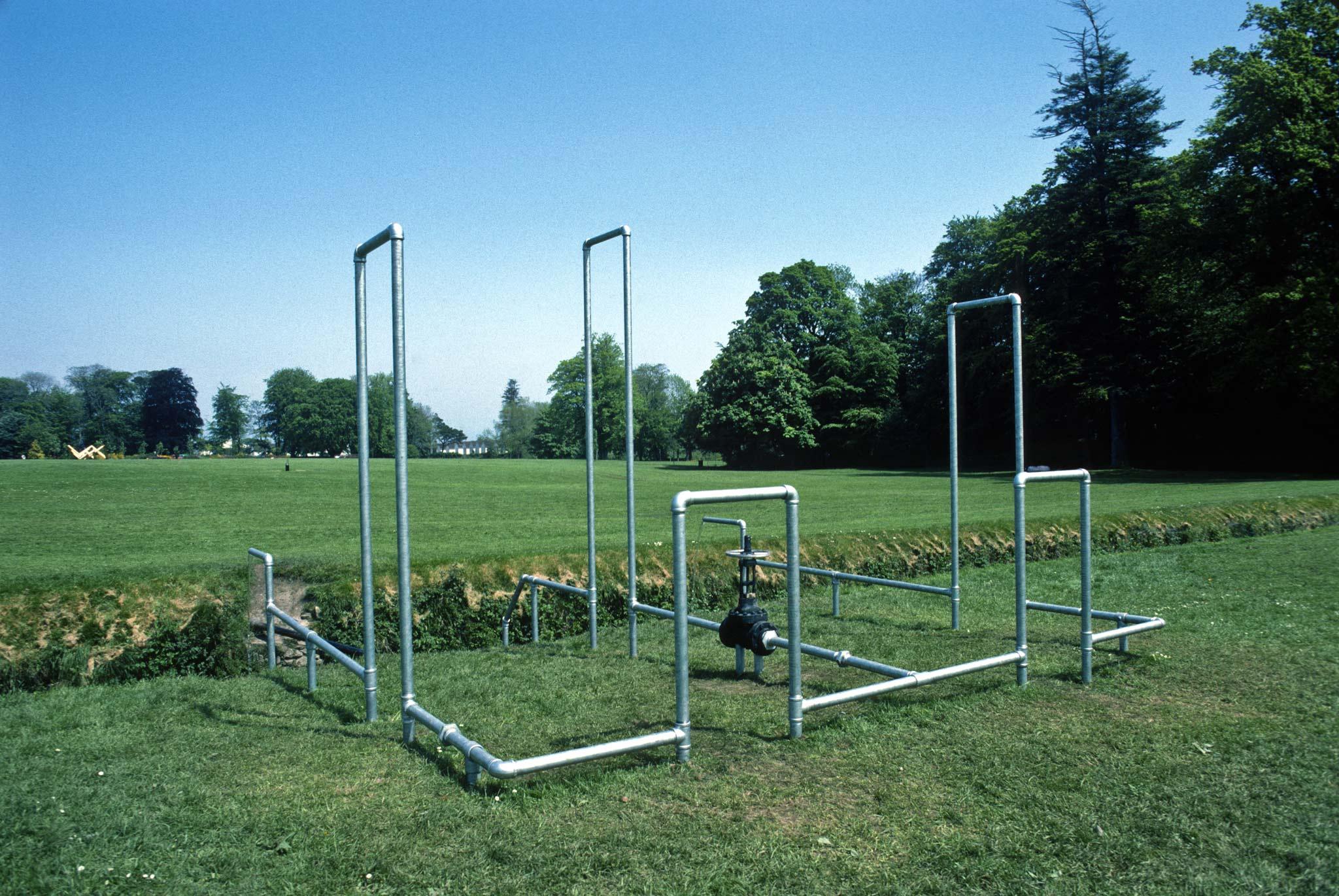 galvanzied pipes organized into rectilinear structures in a field outside a large home in Ireland