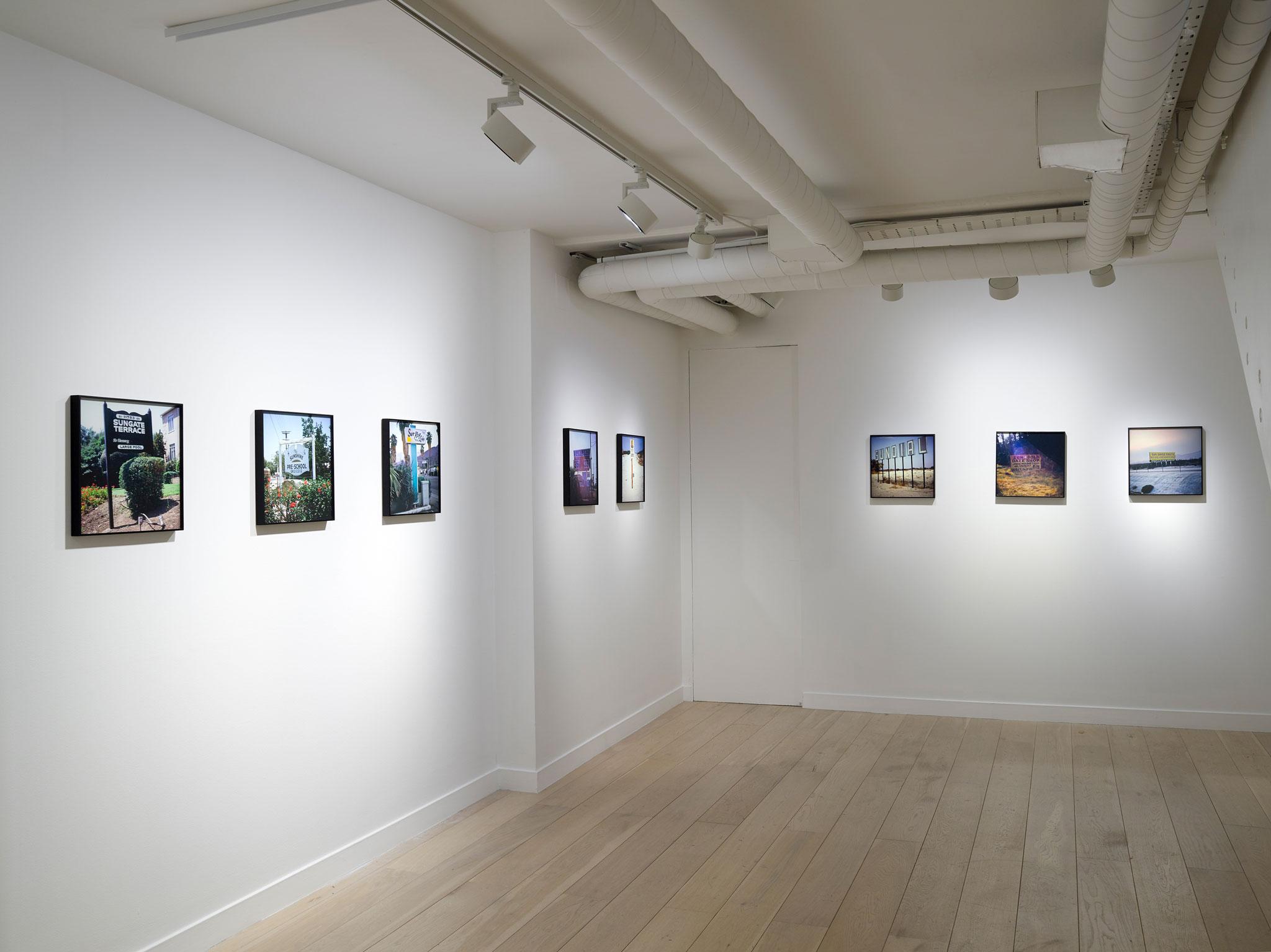framed photographs displayed in a row in a room with white walls and wood floors