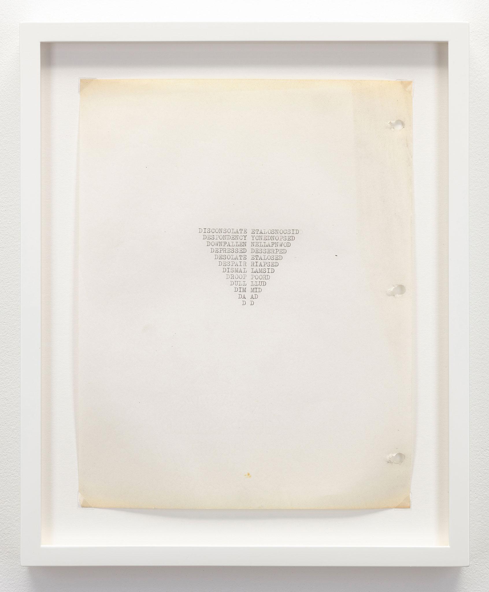 a white frame surrounding a yellowing piece of letter size paper with words typewritten in the shape of an inverted triangle in the center of the paper