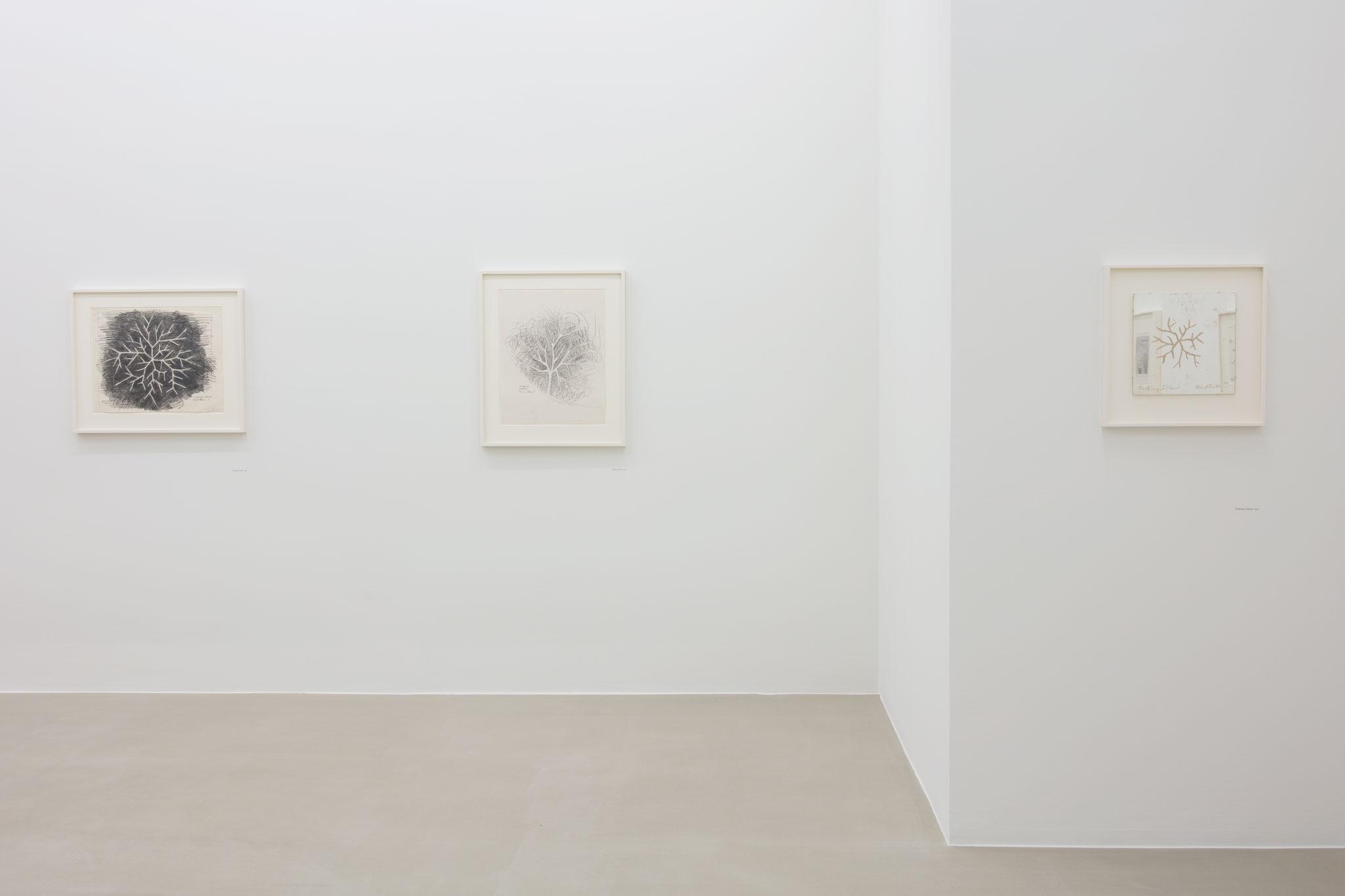three black and white artworks hanging on the white walls of an art gallery