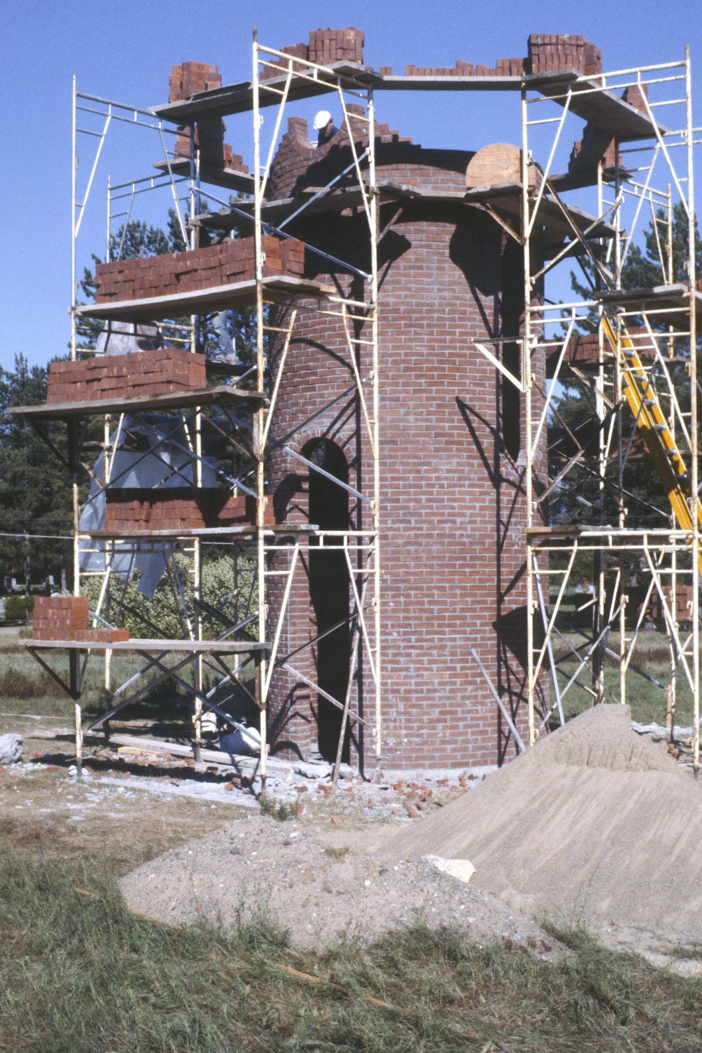Construction showing scaffolding around a large circular tower made of brick