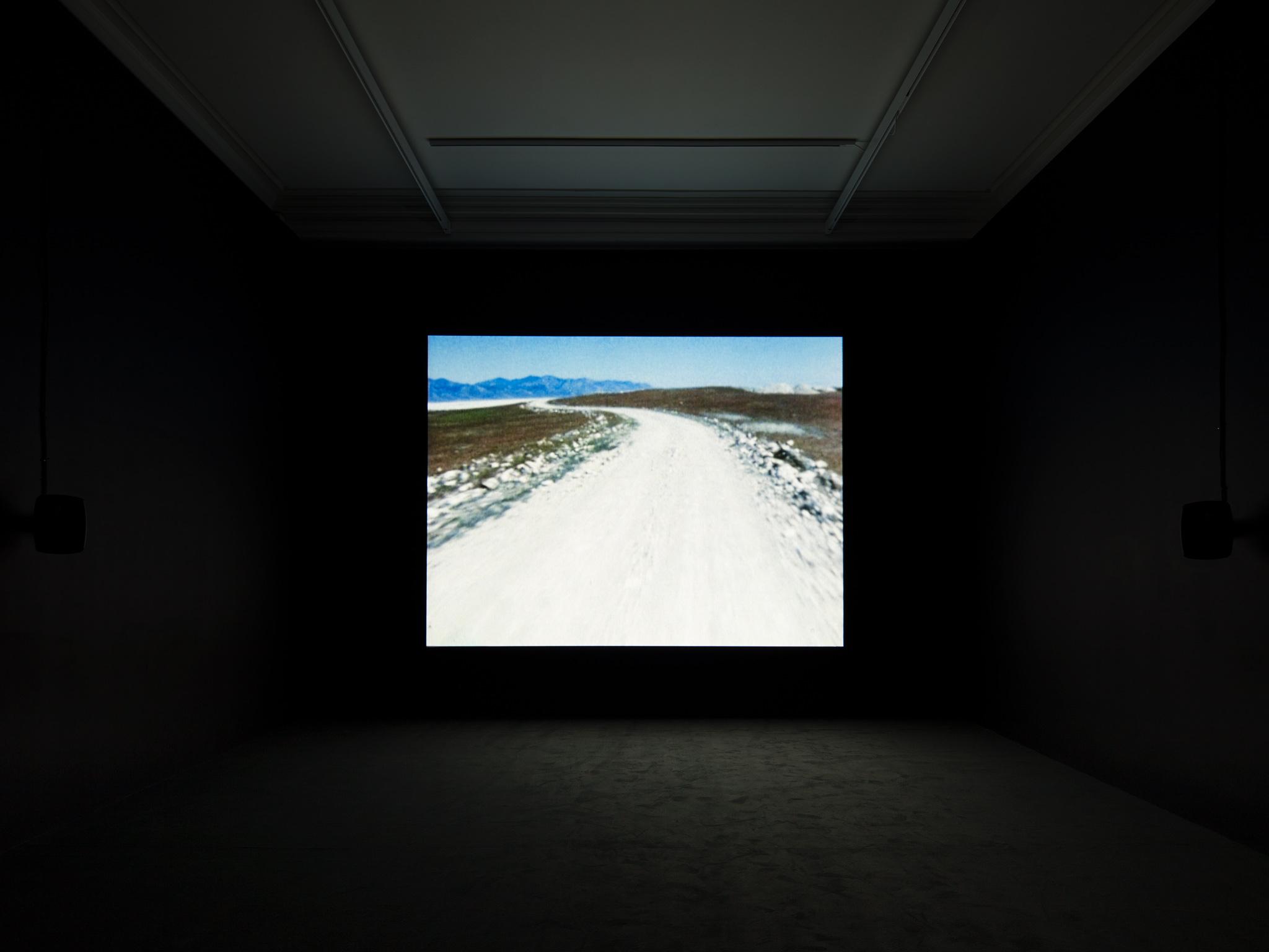 a film screening room with an image of a dirt road projected