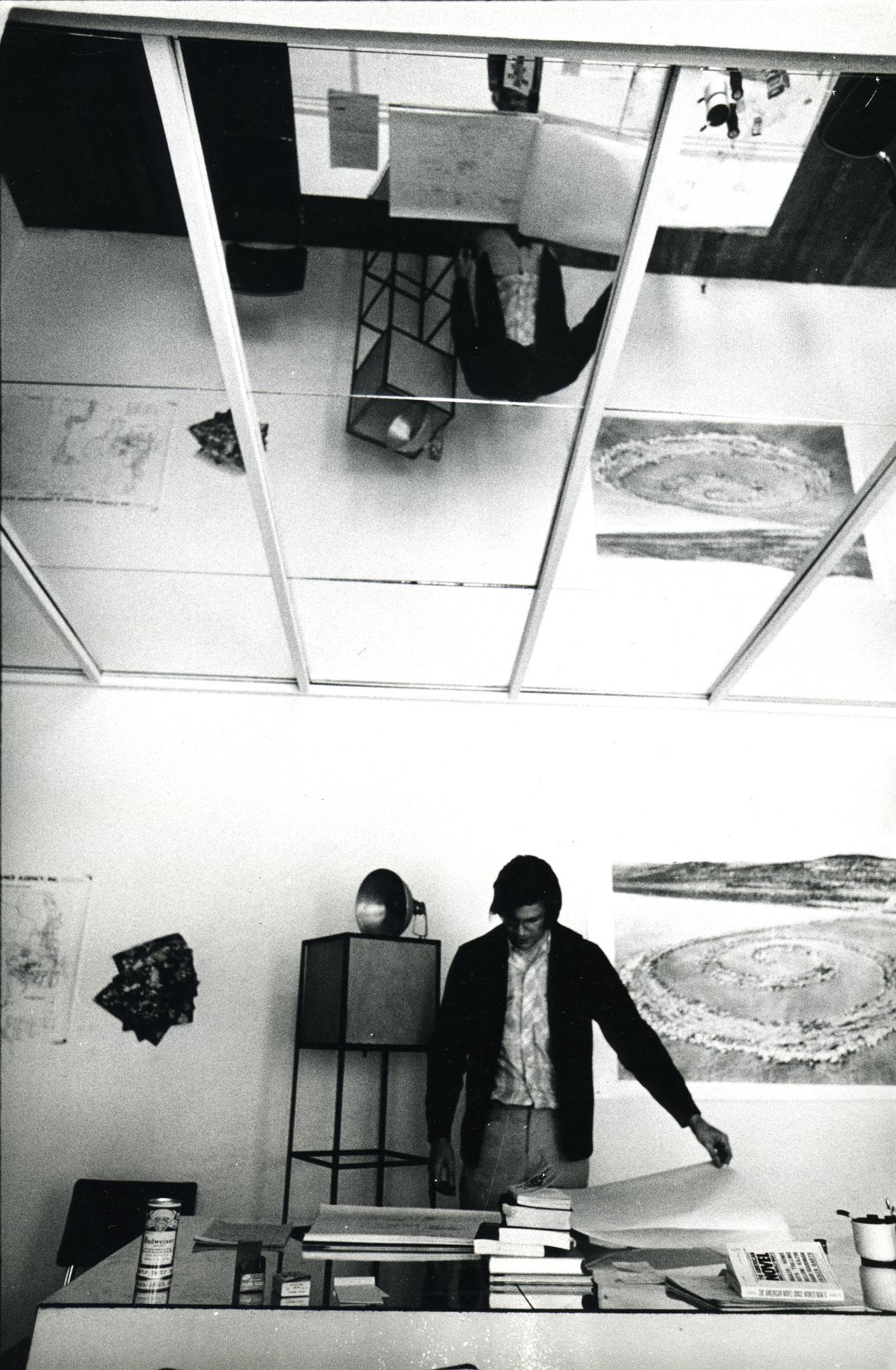 Robert Smithson looking at paper on a mirror table