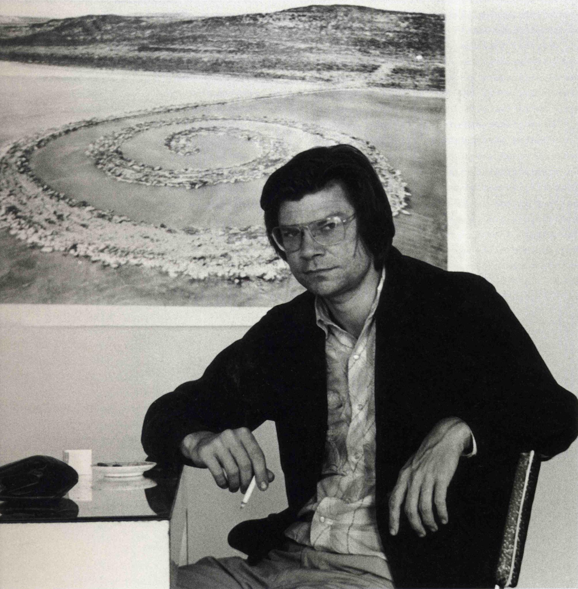 Robert Smithson sitting smoking a cigarette at a table